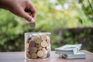 Hand putting coins in jar with money stack step growing growth saving money